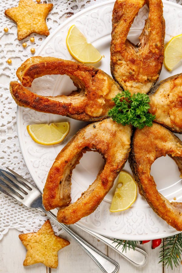 Fried carp fish slices on a white plate, top view. Traditional christmas eve dish.