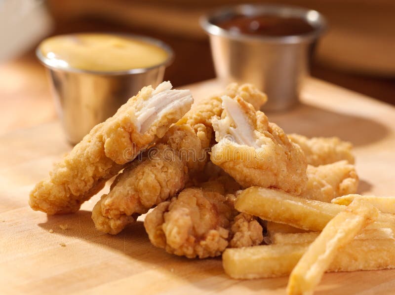 Fried chicken strips with french fries and sauce.