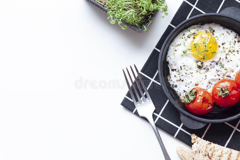Fried Egg in the Black Pan with Tomatoes and Green Sprouts. Healthy