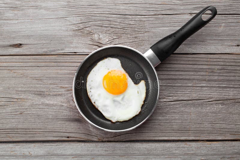 Fried egg in a frying pan, on an old wooden table. Frying pan stock images, royalty-free photos and pictures