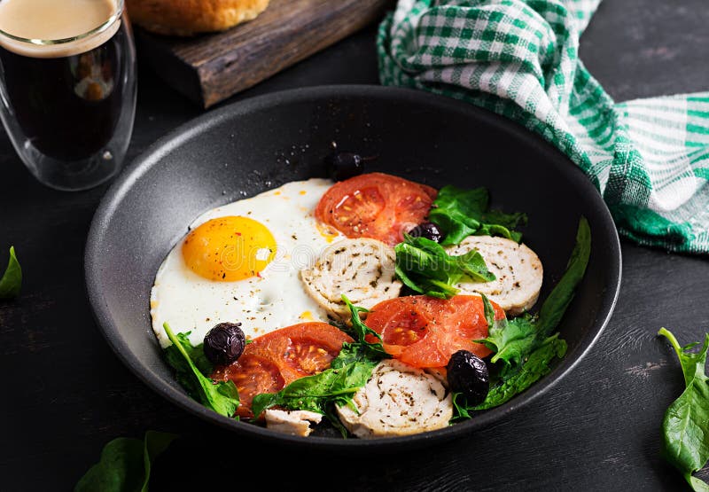 Fried Egg, Meat Roll, Black Olives, Tomatoes and Spinach. Stock Photo