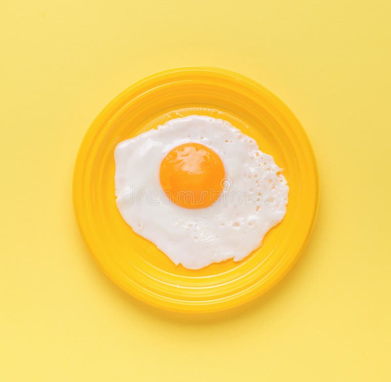 Fried Egg on a Yellow Plate on a Yellow Background. Minimal Concept