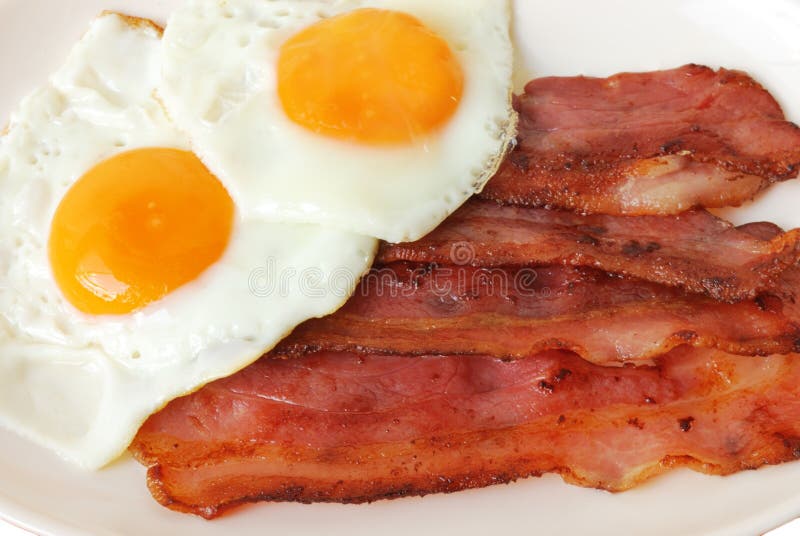 Uova fritte con bacon su placca bianca.