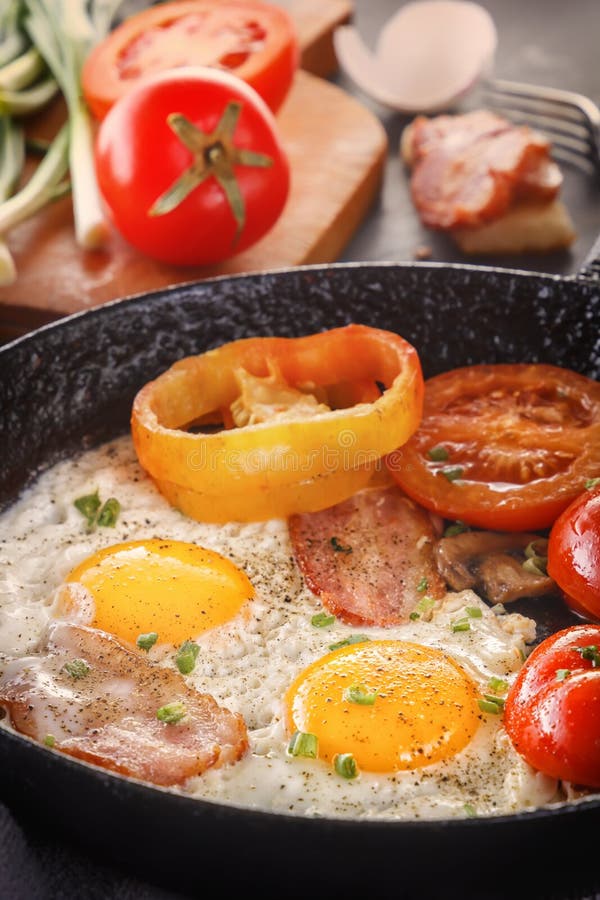 Fried Eggs with Bacon and Tomatoes in an Old Castiron Pan. Stock Photo