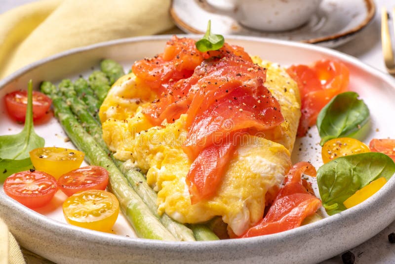 Fried eggs with green asparagus and salmon, cherry tomatoes and fresh spinach