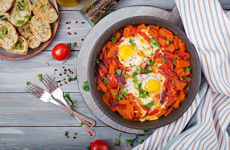 Fried eggs with pieces of pumpkin, red onions and tomatoes