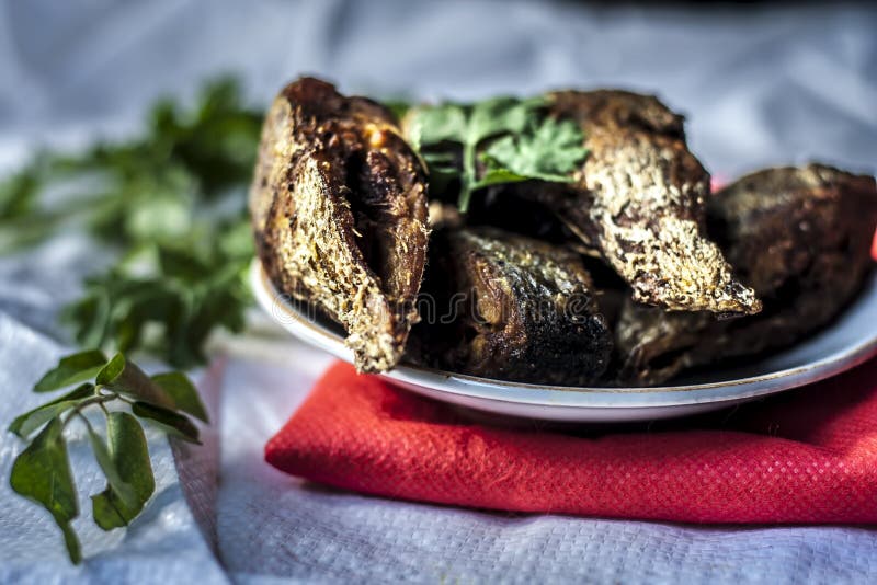 Fried Fish Pieces in a Glass Plate with Curry Leaves. Stock Photo