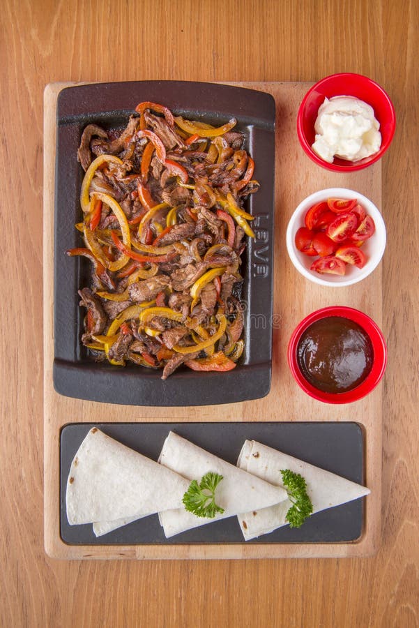 Fried Meat and Vegetables in a Cast Iron Pan with Sauces and Pita Bread