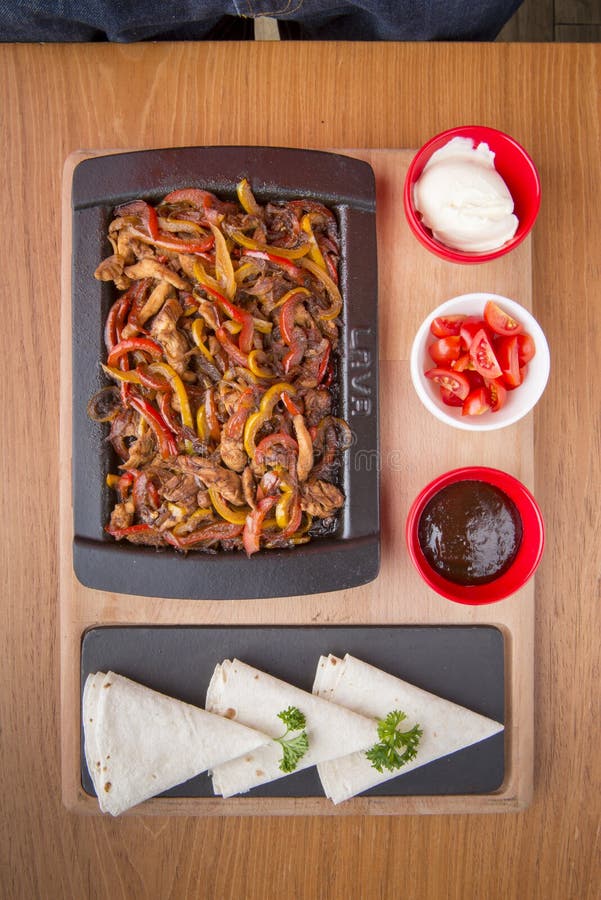 Fried Meat and Vegetables in a Cast Iron Pan with Sauces and Pita Bread