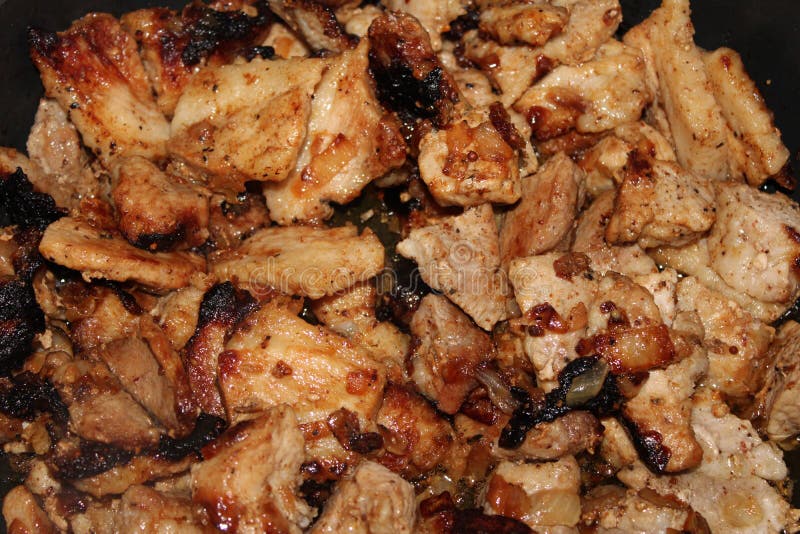 Fried with onions pieces of meat close-up stock photo