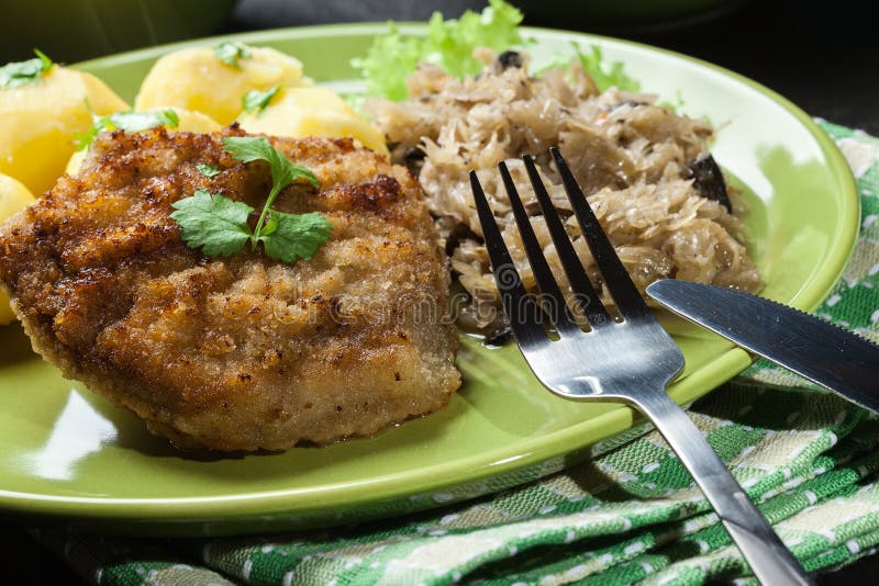 Fried Pork Schnitzel Served with Boiled Potatoes and Fried Sauer Stock