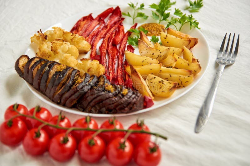 Fried potatoes, eggplant, bell pepper and cauliflower on white plate decorated with silver fork and cherry tomatoes royalty free stock photos Fried potatoes, eggplant, bell pepper and cauliflower on white plate decorated with silver fork and cherry tomatoes royalty free stock photos