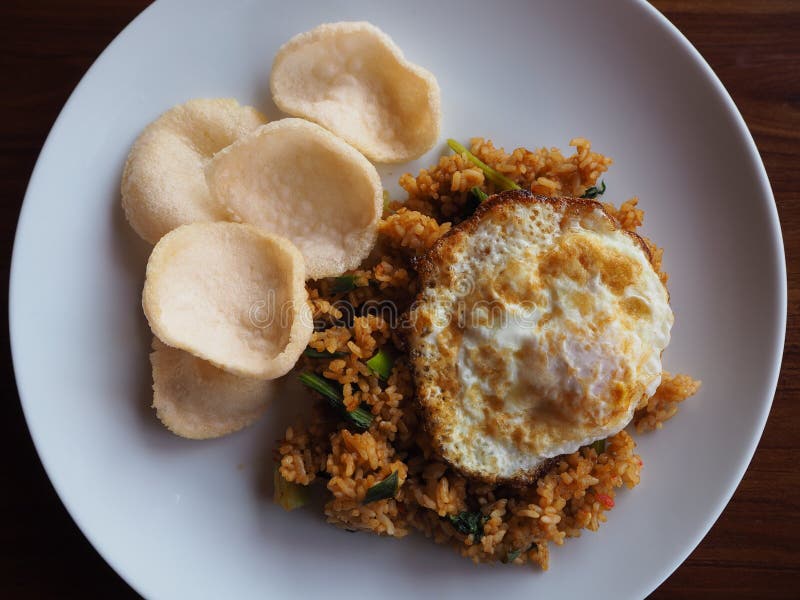 Fried rice, fried eggs, shrimp rice cracker on white dish. Top view