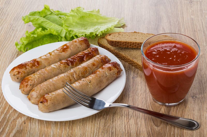 Fried Sausage in Plate, Tomato Juice, Bread and Fork Stock Photo