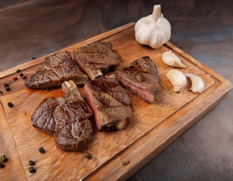Fried steak pieces on a wooden board and garlics vector illustration