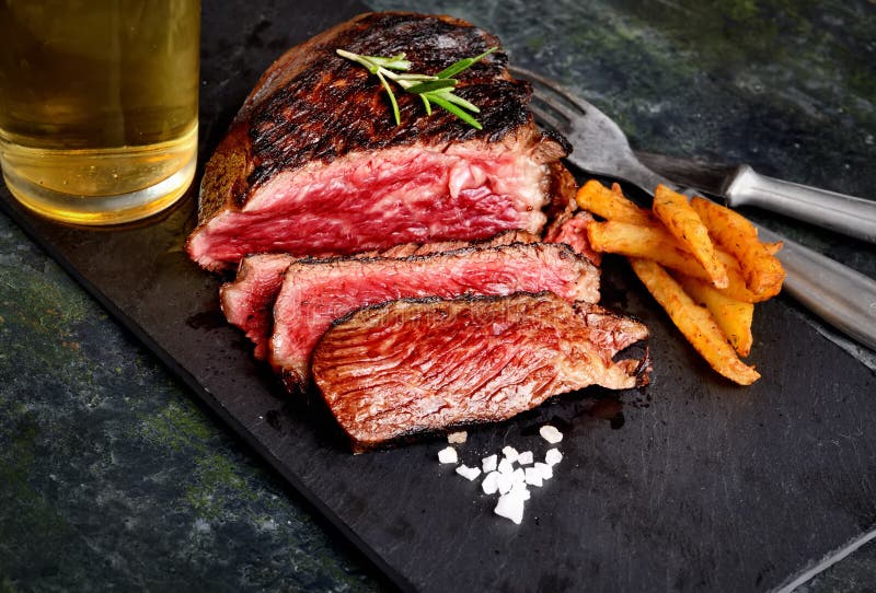 Fried Steak with Rosemary and Spices, Beer, Chips, Fork and Knife on
