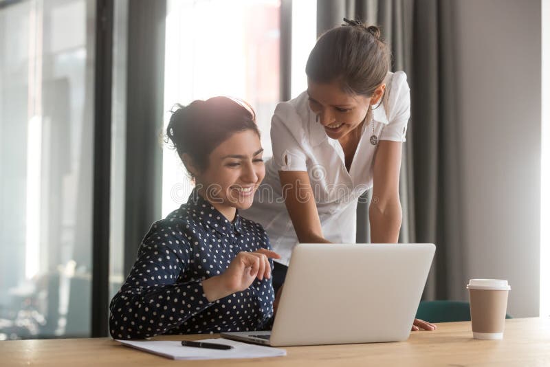 Friendly caucasian mentor supervise indian intern secretary helping with computer