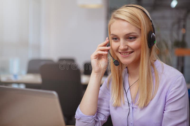 Friendly customer support operator with headset working at call center