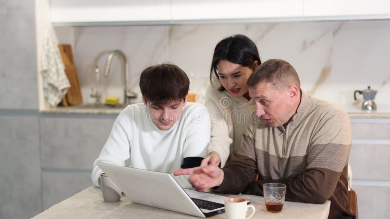 Friendly family watches something together on the Internet or video chats via a laptop.