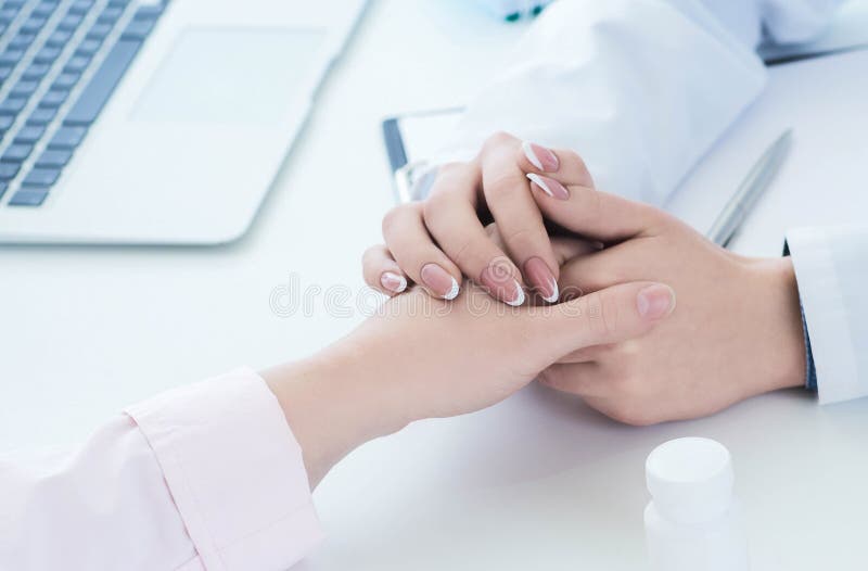 Friendly female doctor hands holding patient hand sitting at the desk for encouragement, empathy, cheering and support royalty free stock photography Friendly female doctor hands holding patient hand sitting at the desk for encouragement, empathy, cheering and support royalty free stock photography