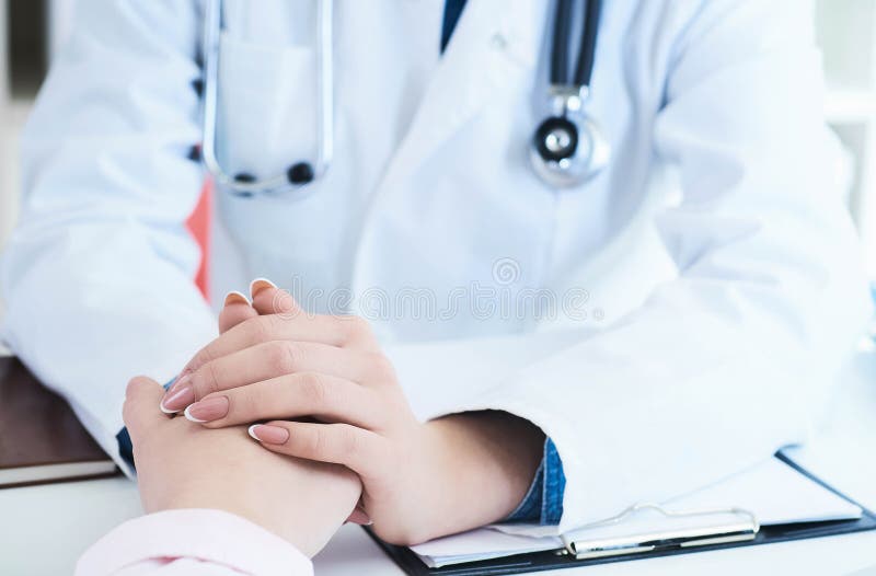 Friendly female doctor hands holding patient hand sitting at the desk for encouragement, empathy, cheering and support royalty free stock photography Friendly female doctor hands holding patient hand sitting at the desk for encouragement, empathy, cheering and support royalty free stock photography