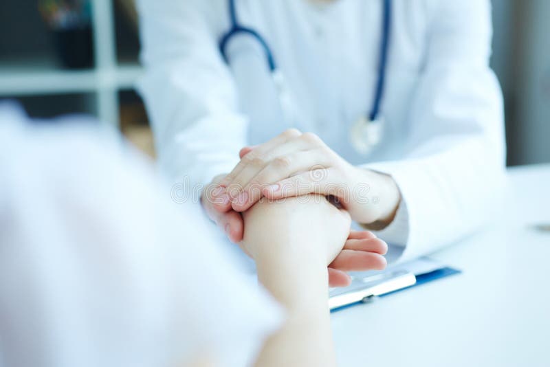 Friendly female doctor`s hands holding female patient`s hand for encouragement and empathy. royalty free stock photos