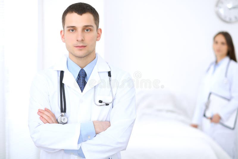 Friendly male doctor on the background of female physician in hospital