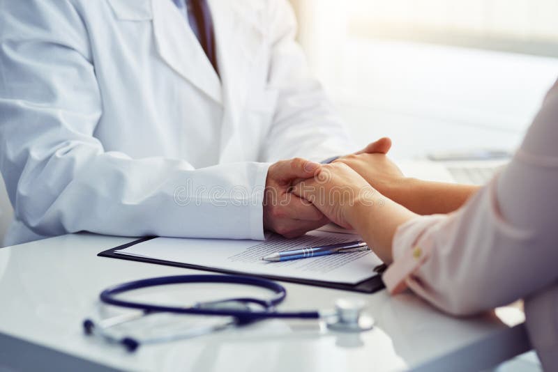 Friendly male doctor reassuring the patient and holding his hands stock images Friendly male doctor reassuring the patient and holding his hands stock images
