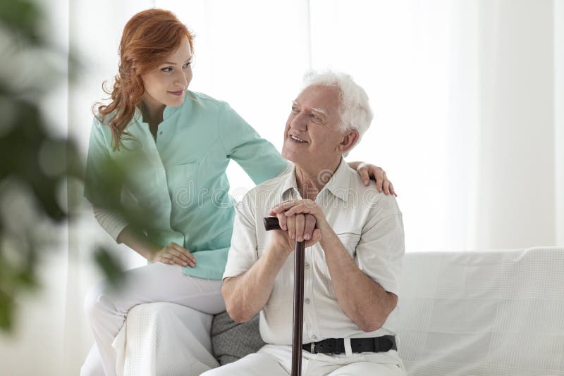 Friendly nurse and smiling elderly man with walking stick in the stock image Friendly nurse and smiling elderly man with walking stick in the stock image