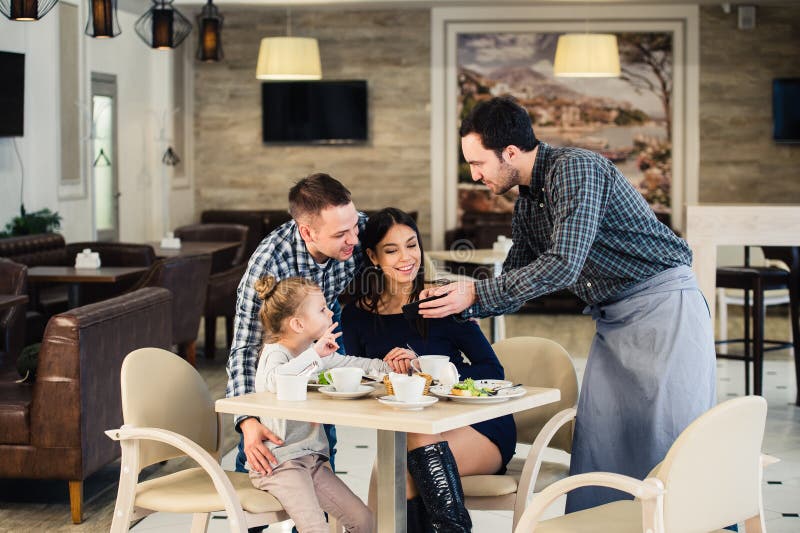 Friendly Smiling Waiter Taking Order at Table of Family Having Dinner