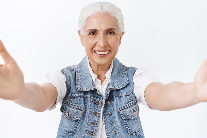 Friendly, tender and kind senior woman with grey combed hair, reaching hands forward, hold camera as taking selfie royalty free stock images Friendly, tender and kind senior woman with grey combed hair, reaching hands forward, hold camera as taking selfie royalty free stock images
