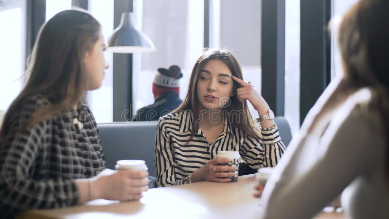 Friends in a cafe bar. Girls drink coffee in a cafe. Three girlfriends are sitting at a table in a cafe.