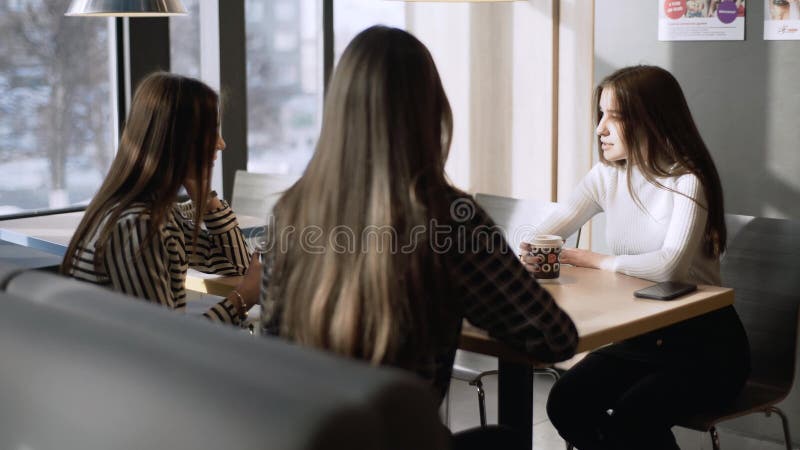 Friends in a cafe bar. Girls drink coffee in a cafe. Three girlfriends are sitting at a table in a cafe.