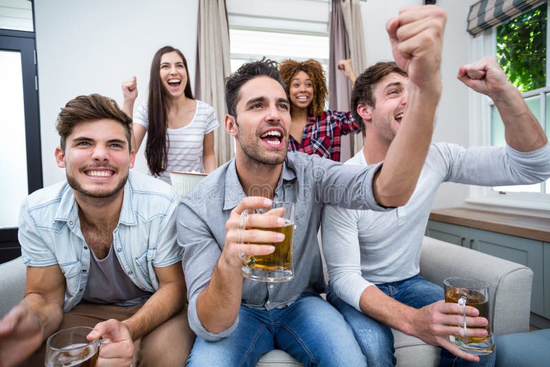 Friends cheering while watching soccer match on TV. Friends cheering and drinking alcohol while watching soccer match on TV royalty free stock photos Friends cheering while watching soccer match on TV. Friends cheering and drinking alcohol while watching soccer match on TV royalty free stock photos