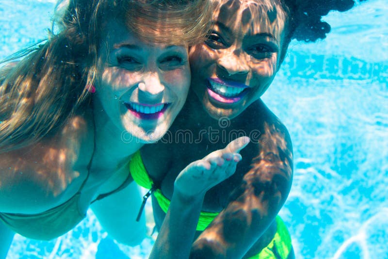 Friends diving underwater in swimming pool.