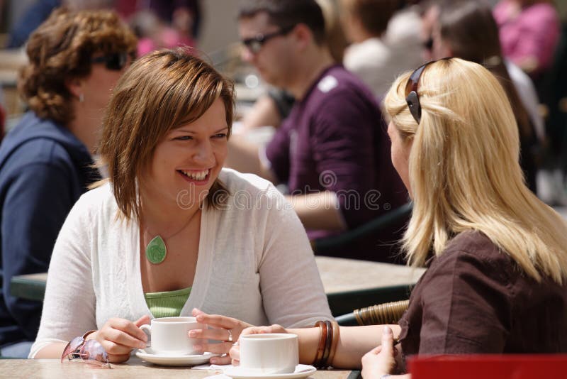 Freunde mit einer Tasse Kaffee an einem Tisch im freien.