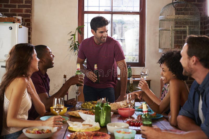 Friends with Drinks at the Table during a Dinner Party Stock Photo