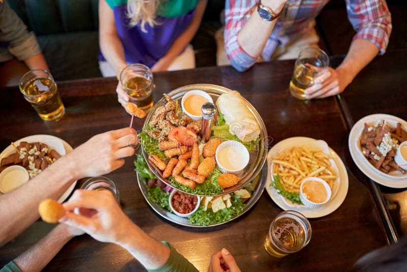 Friends eating and drinking at bar or pub