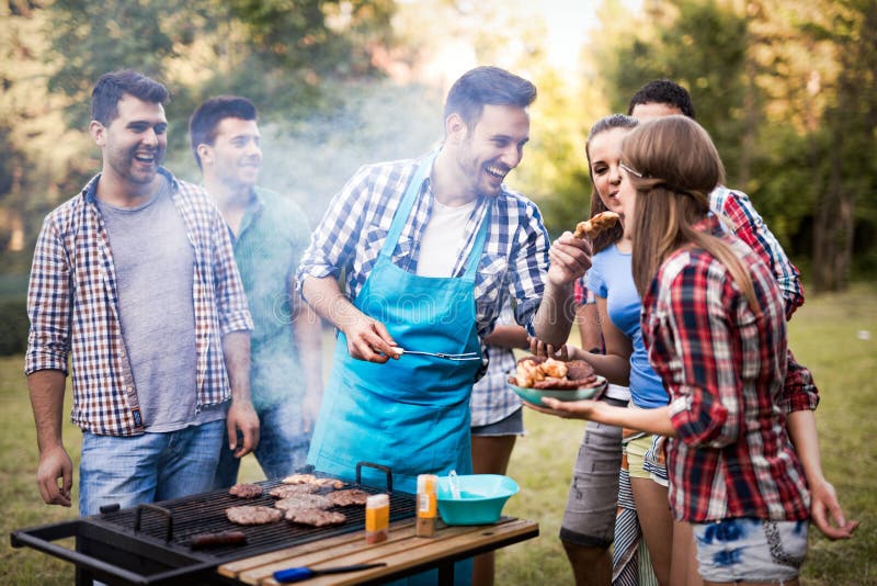 Amici che si divertono a grigliare carne, godendo di un barbecue party.