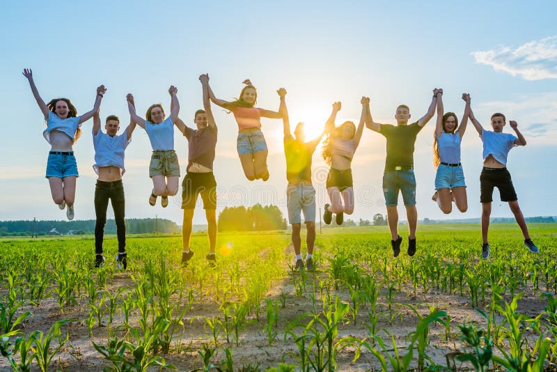 Friends are Jumping Holding Hands at Sunset. Stock Photo Image of