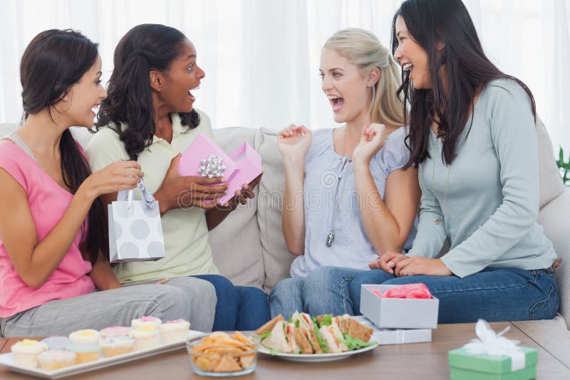 Friends offering gifts to woman during party. Friends offering gifts to women during party at home on couch stock image Friends offering gifts to woman during party. Friends offering gifts to women during party at home on couch stock image