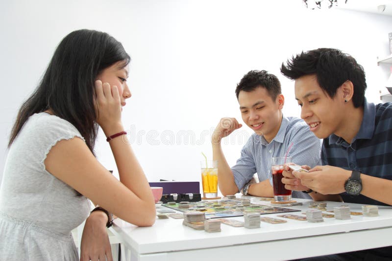 Group of Asian friends playing card games for fun in a hostel