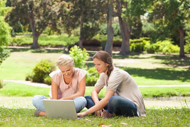 Friends sitting on the lawn with a laptop royalty free stock photography