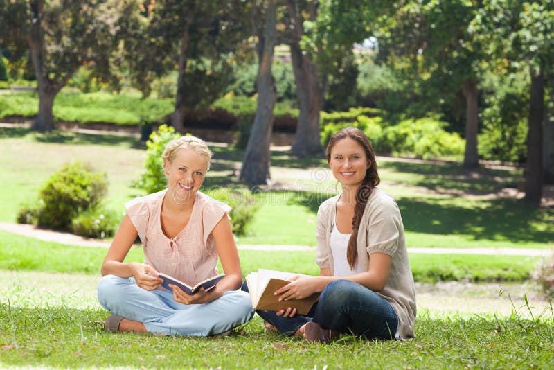 Friends sitting with their books in the park stock photos