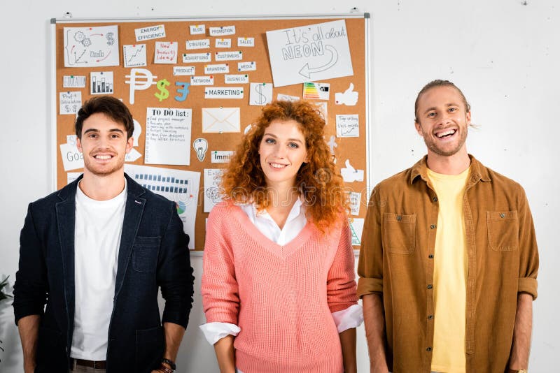 Friends smiling and looking at camera in office stock photography