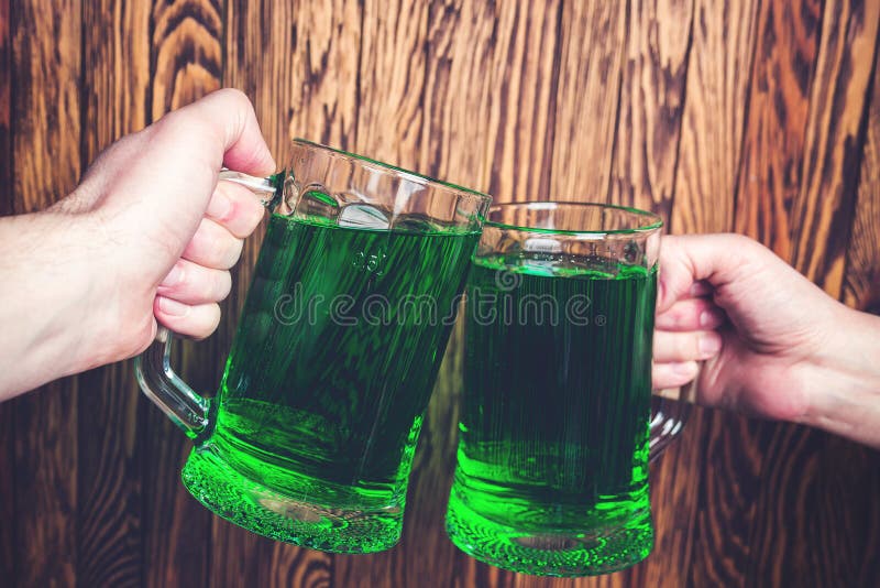 Friends toast with each other. Saint Patrick`s day party. Group of friends is celebrating. Happy people is drinks a green beer