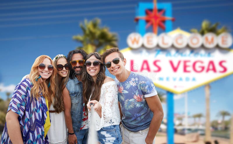 Summer holidays, vacation, tourism and travel concept - group of smiling hippie friends taking selfie by smartphone over welcome to fabulous las vegas sign background. Summer holidays, vacation, tourism and travel concept - group of smiling hippie friends taking selfie by smartphone over welcome to fabulous las vegas sign background