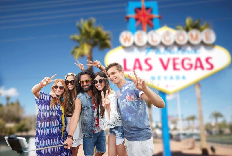 Summer holidays, vacation, tourism and travel concept - group of smiling hippie friends taking selfie by smartphone and showing peace over welcome to fabulous las vegas sign background. Summer holidays, vacation, tourism and travel concept - group of smiling hippie friends taking selfie by smartphone and showing peace over welcome to fabulous las vegas sign background