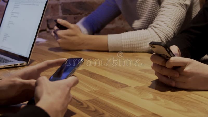 Friends are using modern gadgets at table in trendy place.