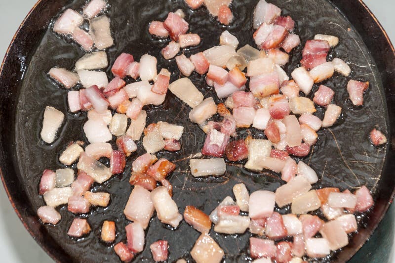 Friggendo bacon affettato sui cubi nella padella fotografie stock Friggendo bacon affettato sui cubi nella padella fotografie stock